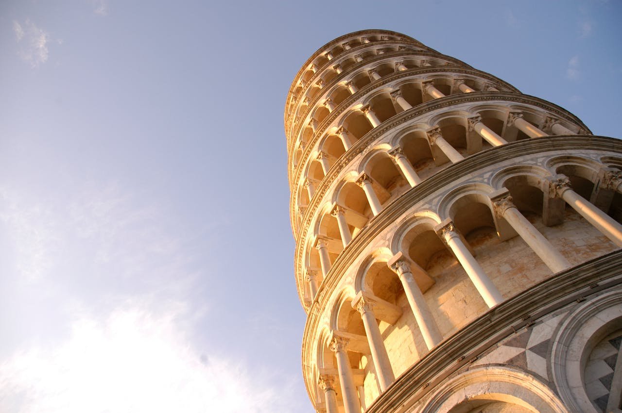 about-02 Low angle view of the Leaning Tower of Pisa, a famous Italian landmark under a clear sky.
